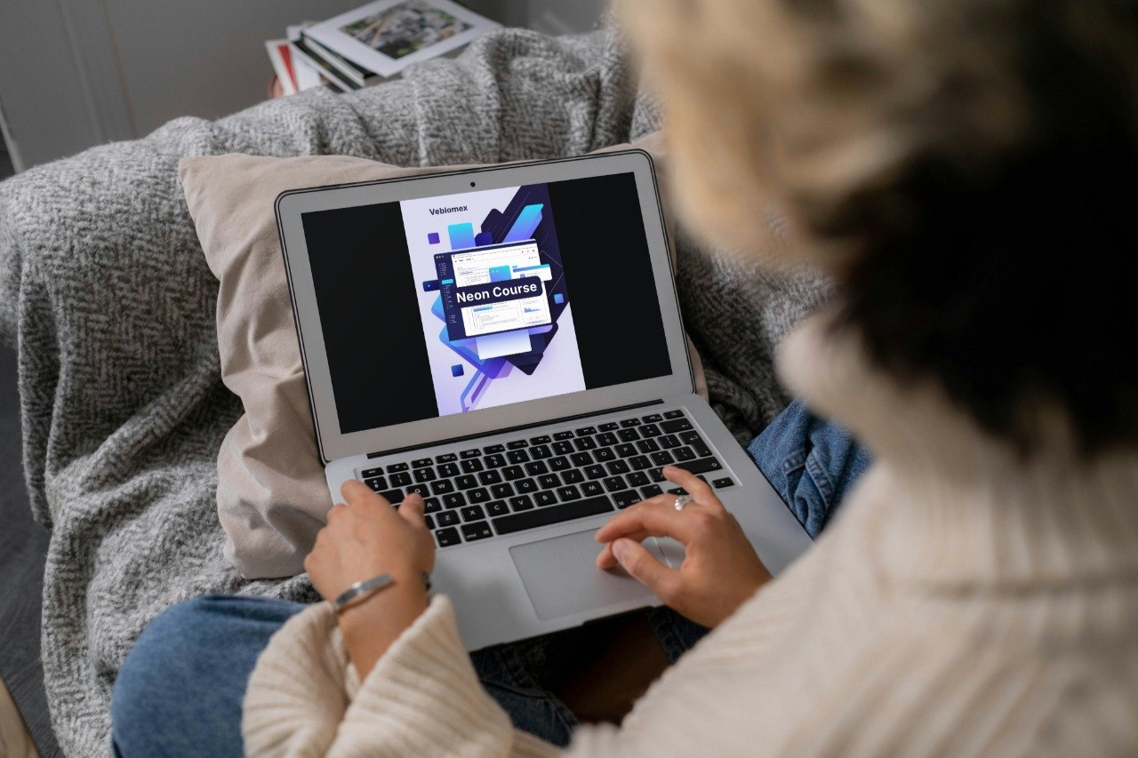 Person using a laptop on a couch with a course interface displayed on the screen.